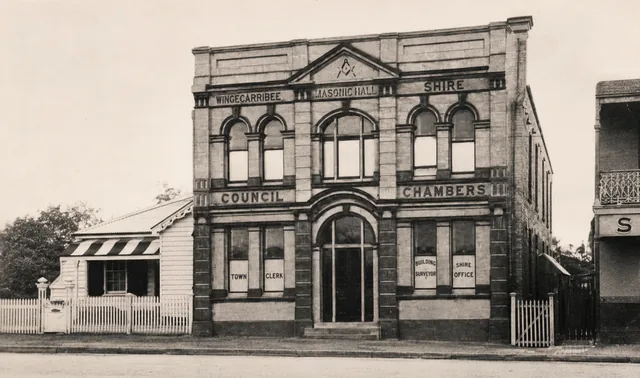 The weatherboard cottage at 374 Argyle Street, left of the former Masonic Hall and council chambers, with a striped awning and white picket fence.