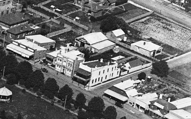 Aerial detail showing 374 Argyle Street beside the former council chambers, with the long stable roof behind the cottage.