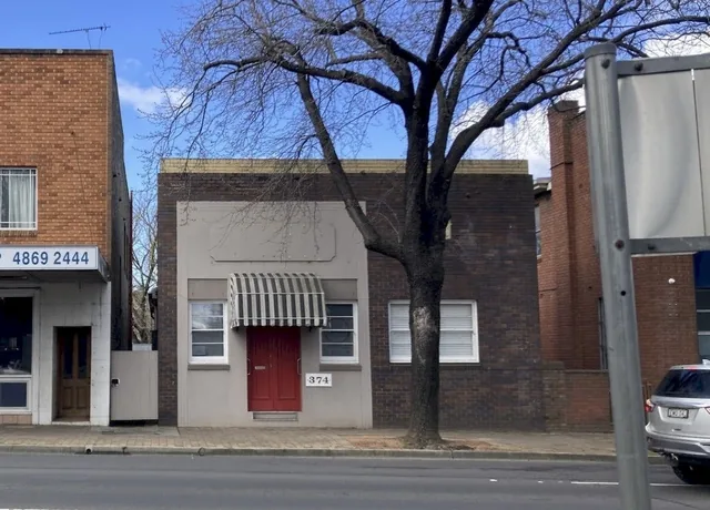 374 Argyle Street in 2026, with a brick street frontage, red front door and striped awning.