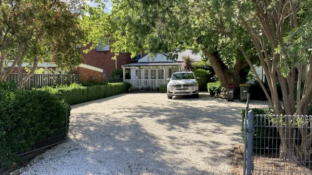 View from Clarence Street in 2026 through the garden and gravel driveway towards the cottage verandah.