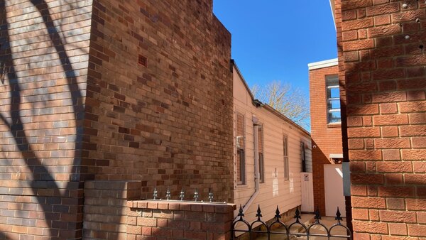 Side view showing the brick commercial frontage at 374 meeting the older weatherboard house
