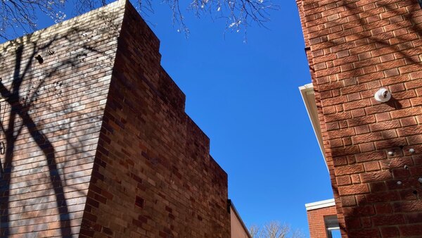 Upward view of the stepped brick parapet above the weatherboard house at 374 Argyle Street